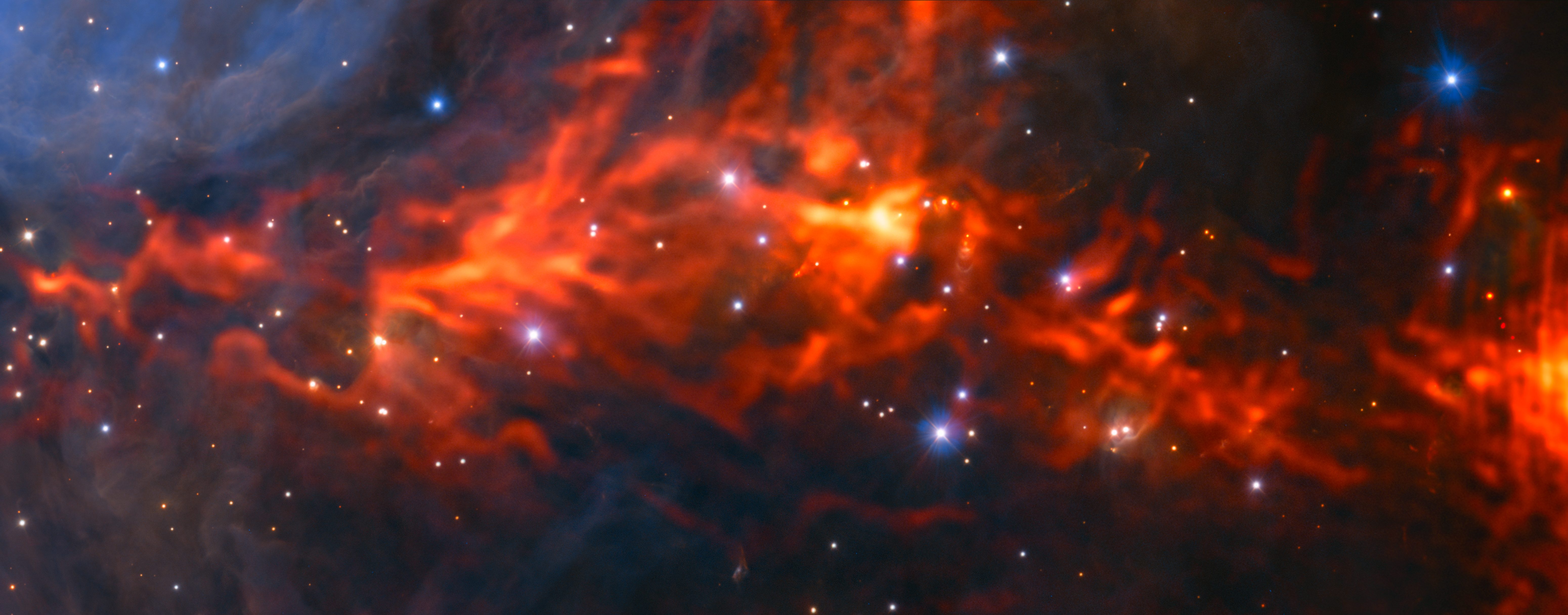 This spectacular and unusual image shows part of the famous Orion Nebula, a star formation region lying about 1350 light-years from Earth. It combines a mosaic of millimetre wavelength images from the Atacama Large Millimeter/submillimeter Array (ALMA) and the IRAM 30-metre telescope, shown in red, with a more familiar infrared view from the HAWK-I instrument on ESO’s Very Large Telescope shown in blue. The group of bright blue-white stars at the left is the Trapezium Cluster, hot young stars that are only a few million years old.